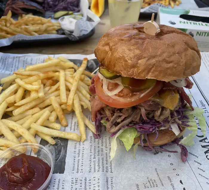 Burger z frytkami i ketchupem na gazecie